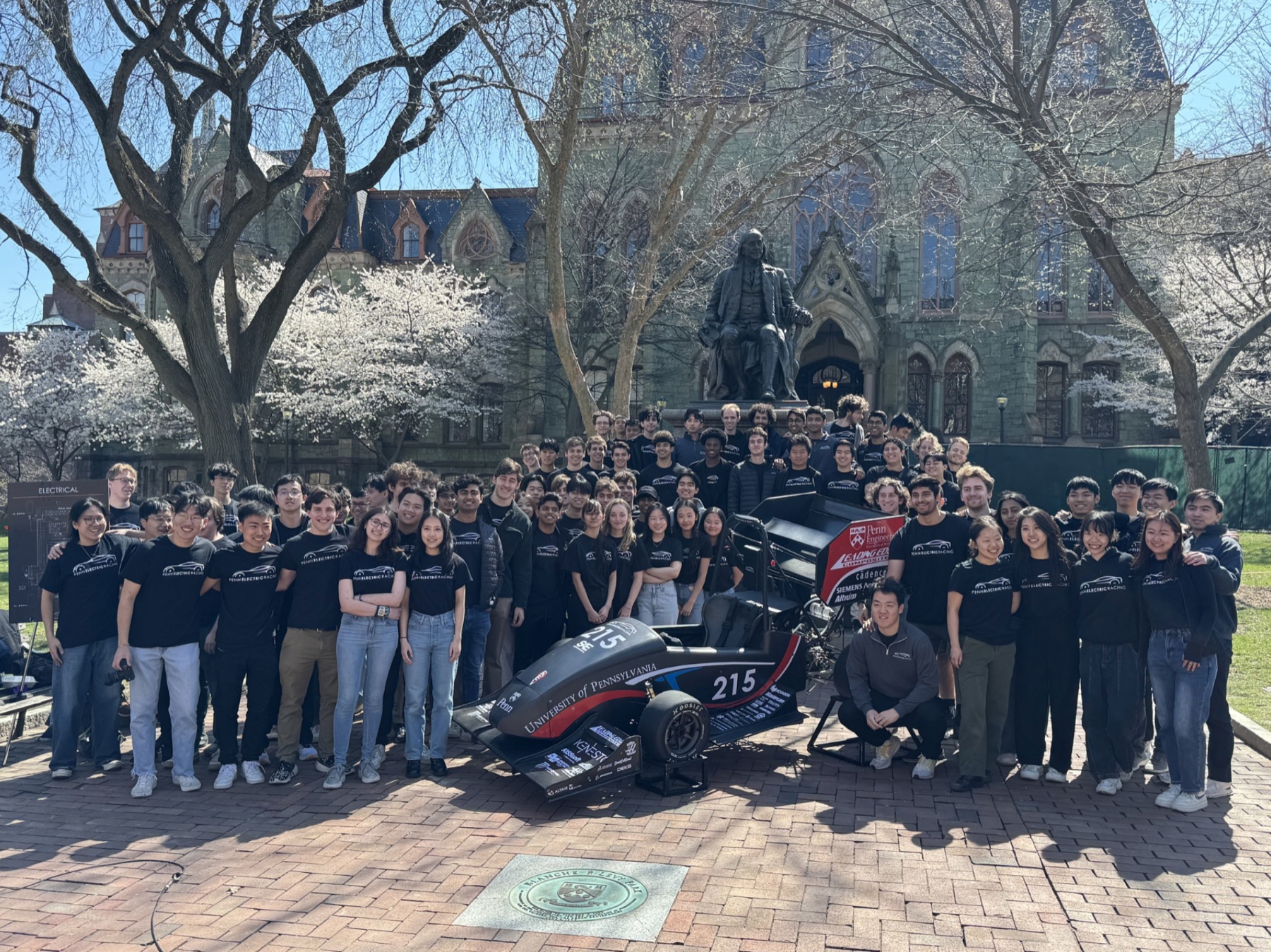 The Penn Electric Racing team on campus with the car